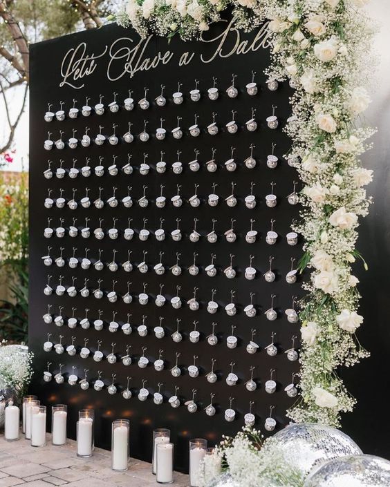 wedding seat chart that is black with babies breath and white roses. the seating chart has disco ball ornaments for each guest